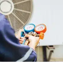 HVAC technician repairing an air conditioning unit outdoors.